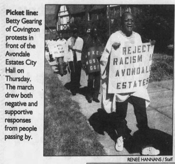 People marching with signs outside AE City Hall